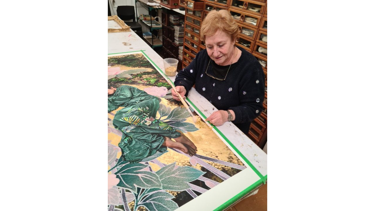 Brigitte gilding with gold leaf on an artwork.
