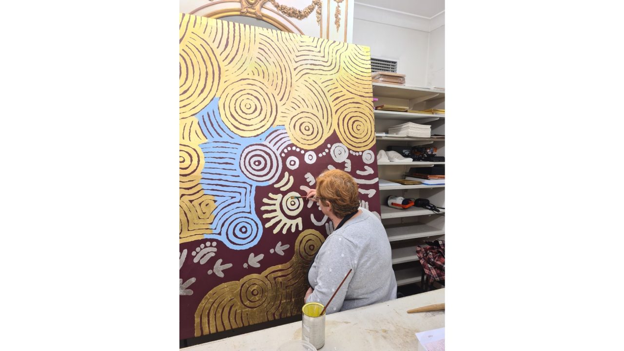 Brigitte working on an Aboriginal artwork with 24k gold leaf and silver leaf on canvas.