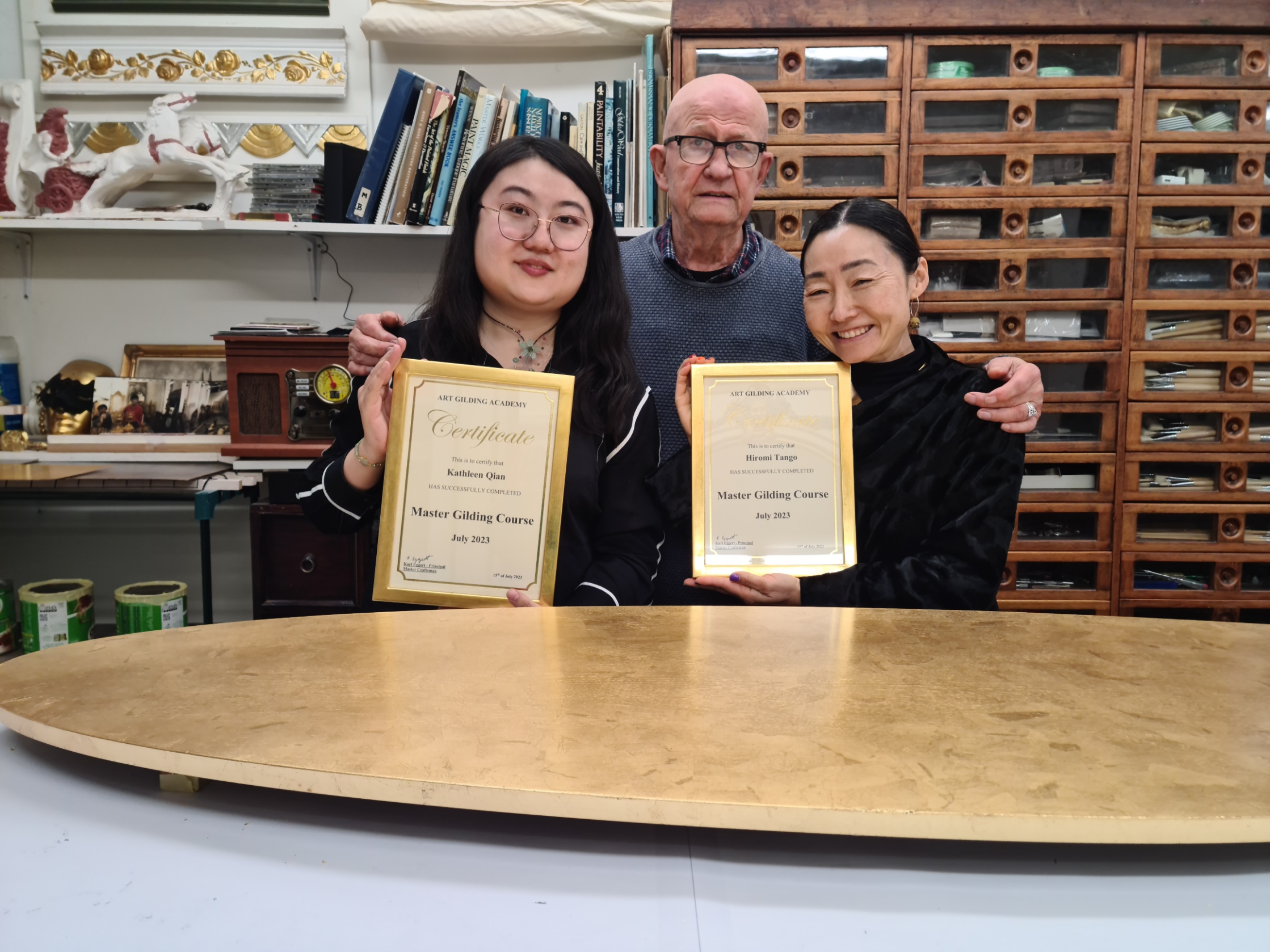 Two students receive their certificates after completing the Art Gilding Masterclass.