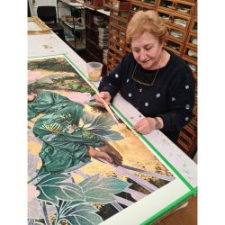 Brigitte gilding with gold leaf on an artwork.