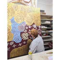 Brigitte working on an Aboriginal artwork with 24k gold leaf and silver leaf on canvas.