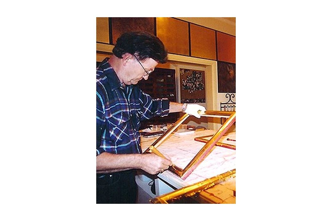 Gold-leafing a frame.