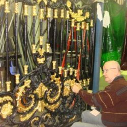 Applying gold leaf while gilding a golden gate outside