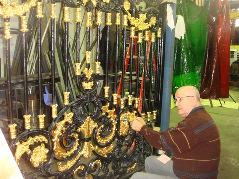 Applying gold leaf while gilding a golden gate outside
