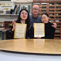 Two students receive their certificates after completing the Art Gilding Masterclass.