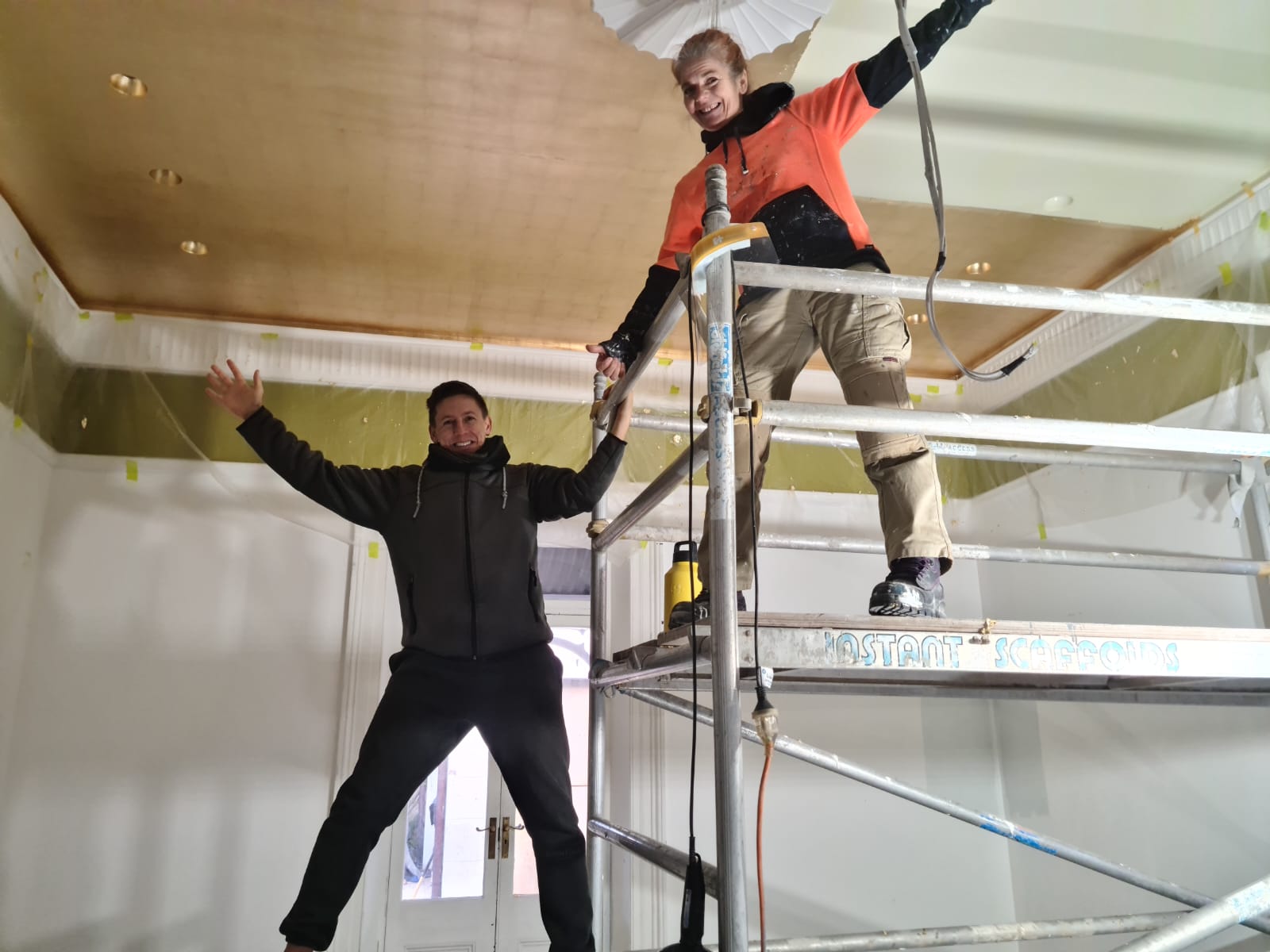 Krissie and Steve applying faux gold leaf over a sprawling 30-square-meter ceiling.